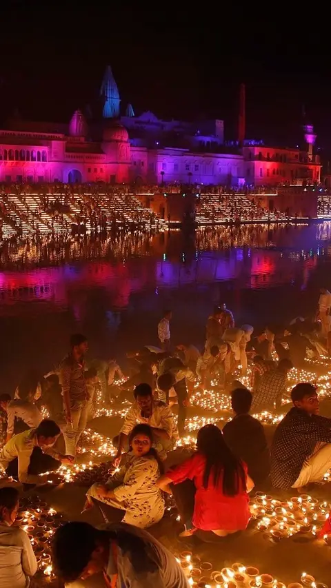 Ghat buildings floodlit in magenta and gold above a crowded riverfront