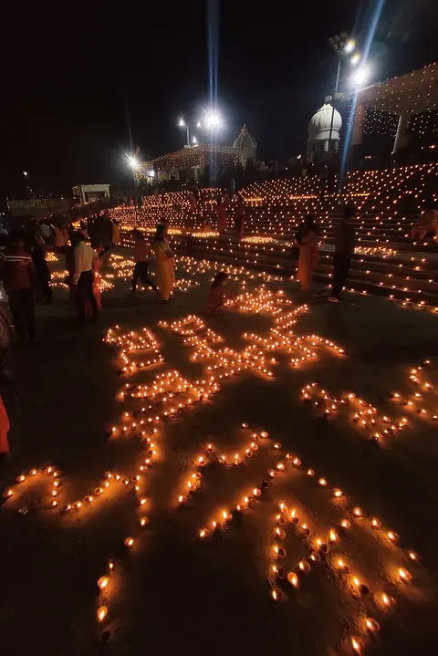 People kneeling among hundreds of lit lamps laid out across the steps