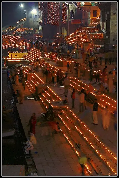 Oil lamps set out in long rows down the stone steps of a ghat