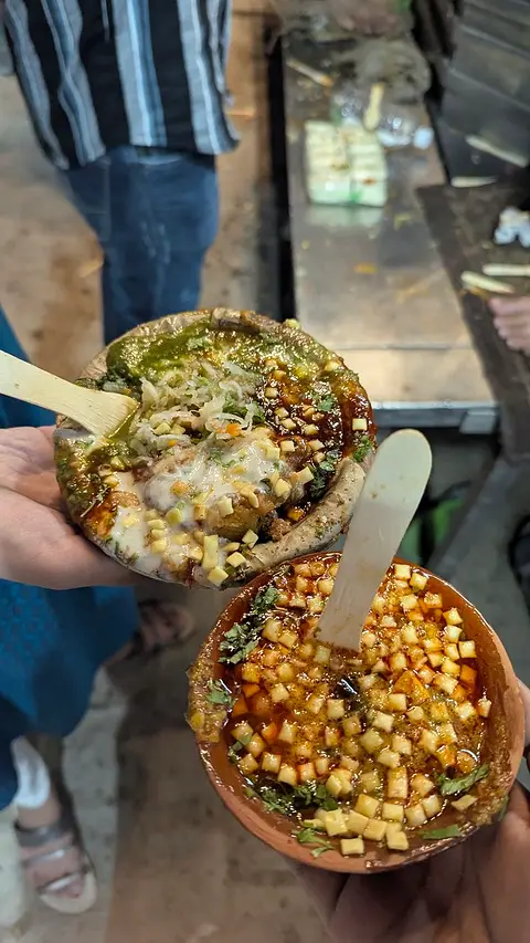 Two bowls of chaat handed across a street stall counter